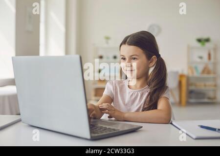 Smiling girl learning online at laptop from home Stock Photo