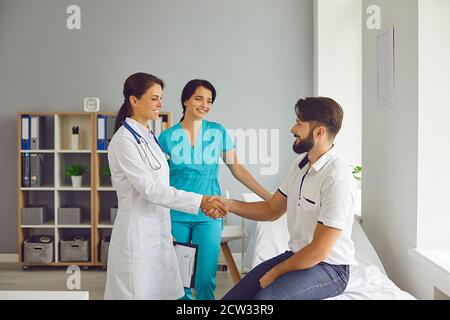 Smiling patient gives a handshake to his doctor at the clinic after the examination. Stock Photo