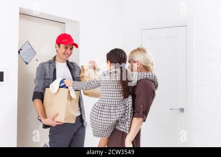 mother and daughter receive order from delivery man, delivery of toys and goods for children at home Stock Photo