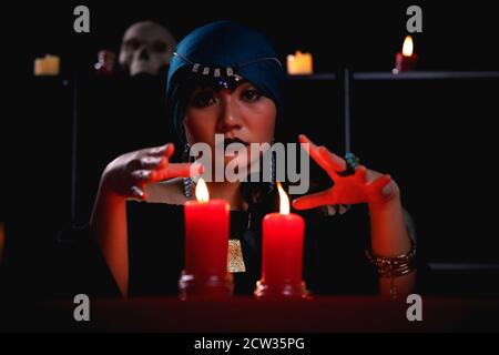 Fortune teller casting spell over red candle during forecasting future. Stock Photo