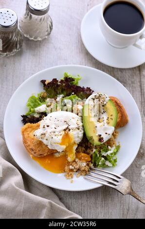 A healthy and balanced breakfast plate. Benedict's egg spreads on a toasted toast with half an avocado, quinoa and lettuce, seasoned   spices and yogu Stock Photo