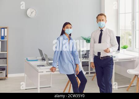 Business colleagues in medical protective mask with documents looking at camera in office Stock Photo