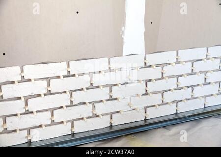 Pieces of the artificial bricks on the wall, installation in progress Stock Photo