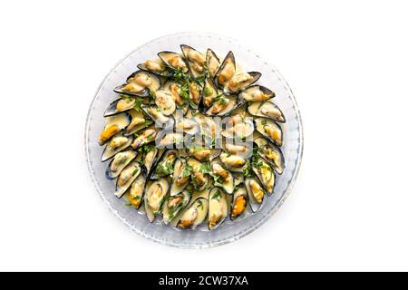 Blue mussels with white wine sauce, onions, garlic and parsley garnish served on a large glass plate, isolated on a white background, high angle view Stock Photo