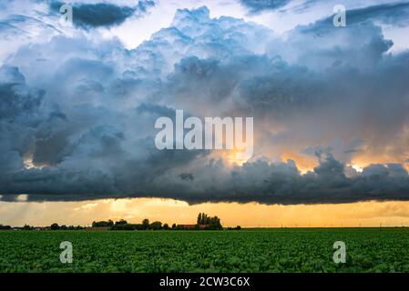 Boiling storm clouds and beautiful colors in the sky over rural landscape at sunset Stock Photo