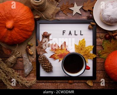 On the table with pumpkins is board with the inscription and a cup of coffee. Stock Photo