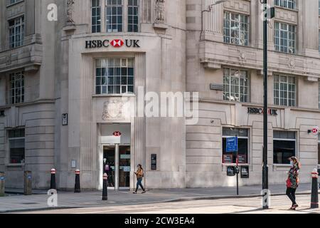 LONDON, ENGLAND - JULY 24, 2020: HSBC Bank plc branch at Holborn, London with a passerby wearing a face mask during the COVID-19 pandemic - 001 Stock Photo