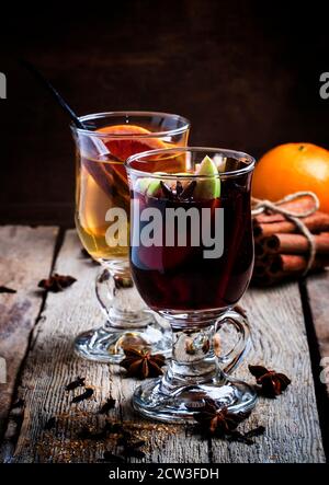 Hot mulled wine with white and red wine, spices and fruits, vintage wooden background, selective focus Stock Photo