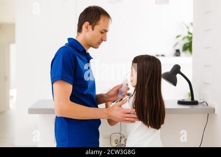 Little toddler girl making inhalation with nebulizer at home. Father helping and holding the device. Child having flu, cough and bronchitis. asthma Stock Photo
