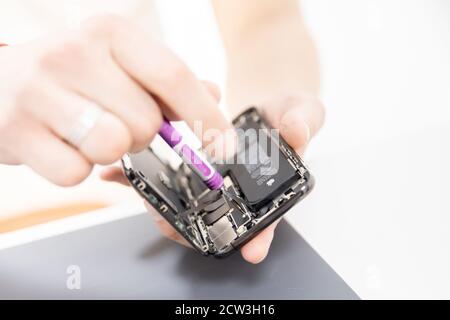 RUSSIA - July 27, 2020: Repair iPhone apple broken phone screen and replace used rechargeable batteries for recycling Stock Photo