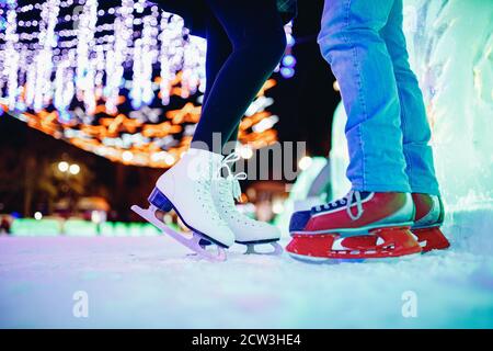 Ice skating lover couple having fun on snow winter holidays night illumination Stock Photo