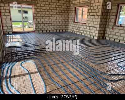 Underfloor heating and cooling installation in brick house, blue pipes for floor heating at the house construction, warm floor during the winter Stock Photo