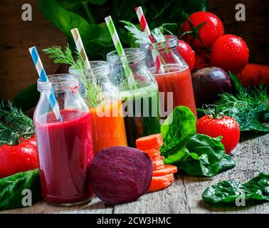 Freshly squeezed vegetable juice in bottles, useful vitamin cocktail, old wooden background, selective focus Stock Photo