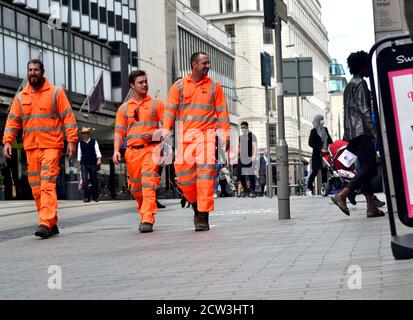 Three workers in orange reflective uniforms on Corporation Street, Birmingham Stock Photo