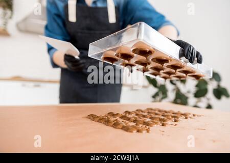 Confectioner girl holds form for candy made of Belgian chocolate Stock Photo