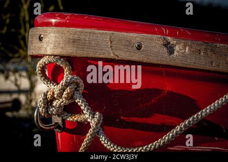 A close up of boat ropes tied up around the cleat on the bow of a wooden boat using selective focus Stock Photo