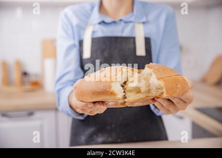 Baker hands break hot fresh round wheat bread into two halves, crunch and crumbs Stock Photo