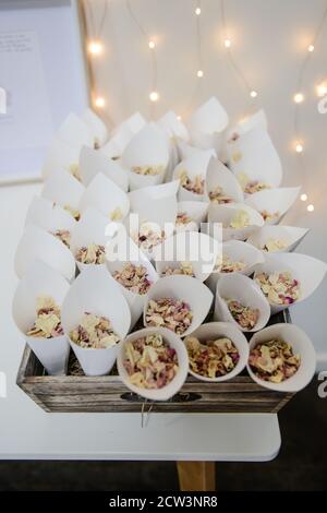 Rose Petal Confetti in cream paper cones and wooden basket photographed from above Stock Photo