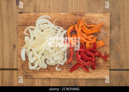 chopped onion chopped orange pepper chopped red pepper shot from above on wooden chopping board Stock Photo