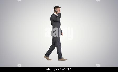Businessman walking and talking on mobile phone on gradient back Stock Photo