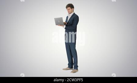 Concentrated young businessman working on laptop while standing Stock Photo