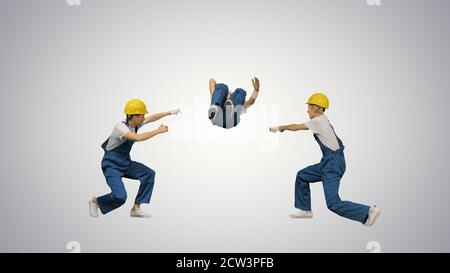 Three young construction workers in hard hats synch dancing look Stock Photo