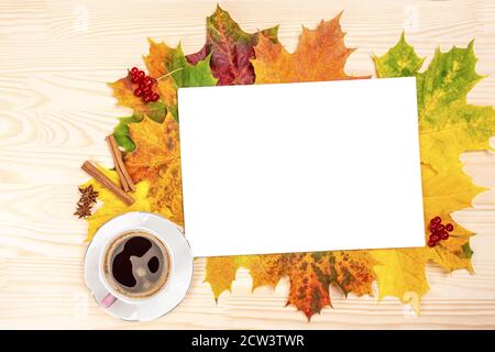 mockup Autumn flat lay composition. Cup of coffee, white blank paper, cinnamon sticks, fallen leaves on white wooden desk. Cozy autumn flat lay mockup Stock Photo