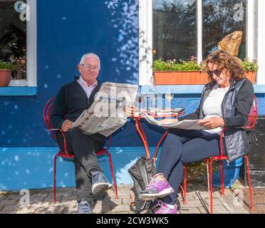 Kenmare, Kerry, Ireland. 27th September, 2020. Retired couple Gerry and Noëlle McCoy from Waterford reading the day's papers on a bright autumanal afternoon  during their staycation outside the Tom Crean Bar on Main Street, Kenmare, Co. Kerry, Ireland. - Credit; David Creedon / Alamy Live News Stock Photo