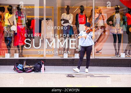 Busker  street entertainer playing the violin or fiddle in the shopping area  of the high street in the of the city of Oxford England Stock Photo
