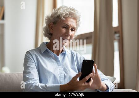Happy elegant old lady using smartphone with confidence at home Stock Photo