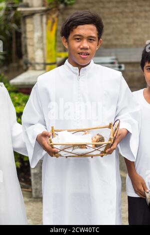 A image of the baby Jesus is held by a sacristan. His entourage visit catholic houses during Christmas time Stock Photo