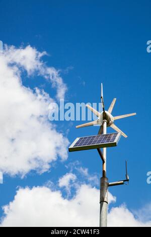 Wind turbine and solar  panel combined to provide electricity on a small scale to power a road sign Stock Photo