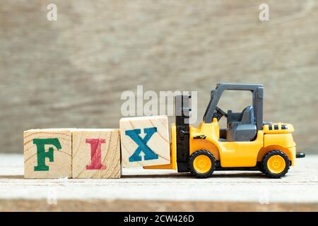 Toy forklift hold letter block x to complete word fix on wood background Stock Photo