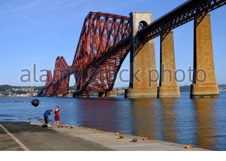 South Queensferry, Scotland, UK. 27th Sep 2020. Fine weather brings out the visitors to South Queensferry, photographer and model in photoshoot in front of the Forth Bridge on Hawes pier. Credit: Craig Brown/Alamy Live News Stock Photo