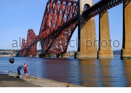 South Queensferry, Scotland, UK. 27th Sep 2020. Fine weather brings out the visitors to South Queensferry, photographer and model in photoshoot in front of the Forth Bridge on Hawes pier. Credit: Craig Brown/Alamy Live News Stock Photo