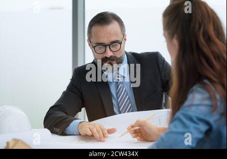 Team of multiethnic architects working on construction plans in meeting room. Engineers discussing on project in office. Stock Photo