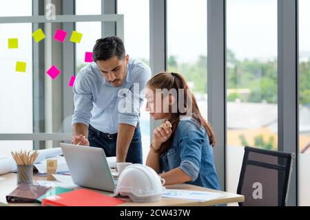 Team of multiethnic architects working on construction plans in meeting room. Engineers discussing on project in office. Stock Photo