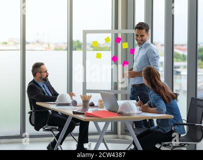 Team of multiethnic architects working on construction plans in meeting room. Engineers discussing on project in office. Stock Photo