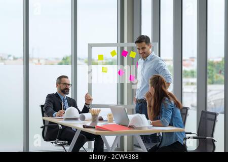 Team of multiethnic architects working on construction plans in meeting room. Engineers discussing on project in office. Stock Photo
