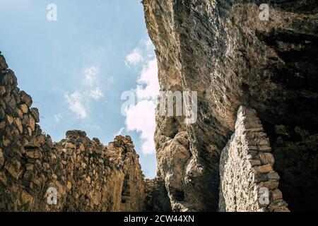 Close up of view of mountain from destroyed cave on sunny day. Ancient stone cave of old town located in rock. Stock Photo