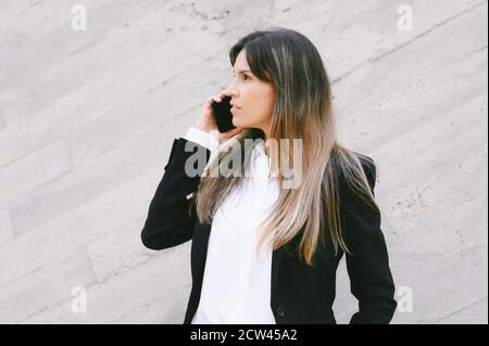 Close up, businesswoman in suit. Businesswoman with serious expression talking phone outdoors. High quality photo Stock Photo