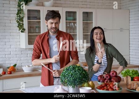 Cooking together. Happy and beautiful young family couple having fun while preparing healthy food in the modern kitchen at home, enjoying free time Stock Photo