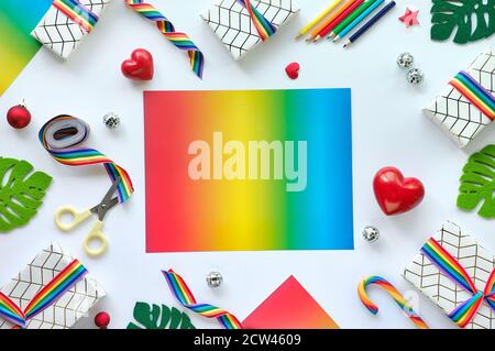 Frame made of Christmas gifts with rainbow ribbon in LGBTQ community flag colors. Flat lay, Xmas decor, copy-space. Stock Photo