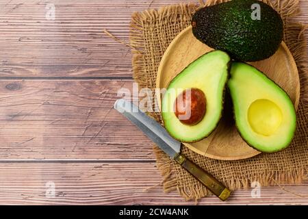 Avocado half on wood plate on wood background and copy space. Ripe fresh green avocado Stock Photo