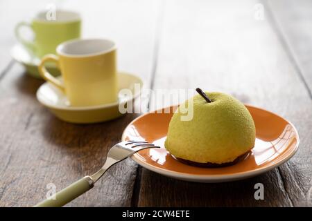 Two Small French ball shaped cakes mousse dome served on a plate with cups of tea Stock Photo