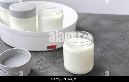 homemade yogurt making, glass jars with kefir. fermented dairy product made in yogurt making machine. probiotic food for gut health. good digestion concept.  Stock Photo