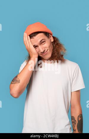 Young adult guy holding hand near face Stock Photo