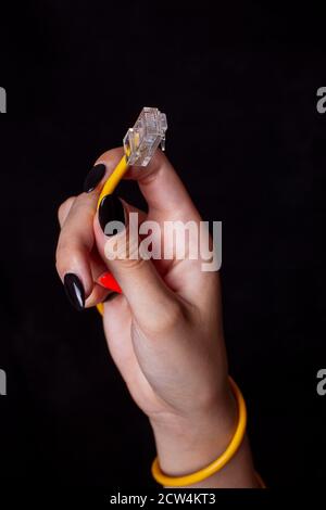 Hand holding yellow Cable Network RJ45 Lan Internet isolated on black Background Stock Photo