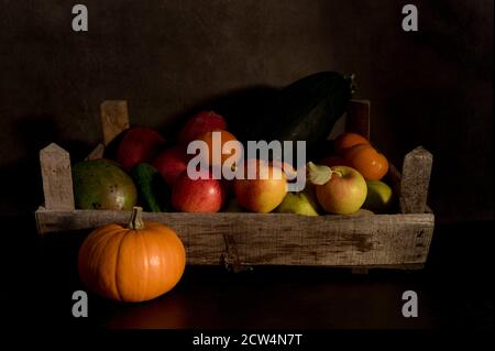 a still life of fruit in an old wooden box with a brown and black mixed background Stock Photo