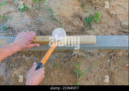 Worker laying red and gray concrete paving blocks. Road Paving, construction. Stock Photo